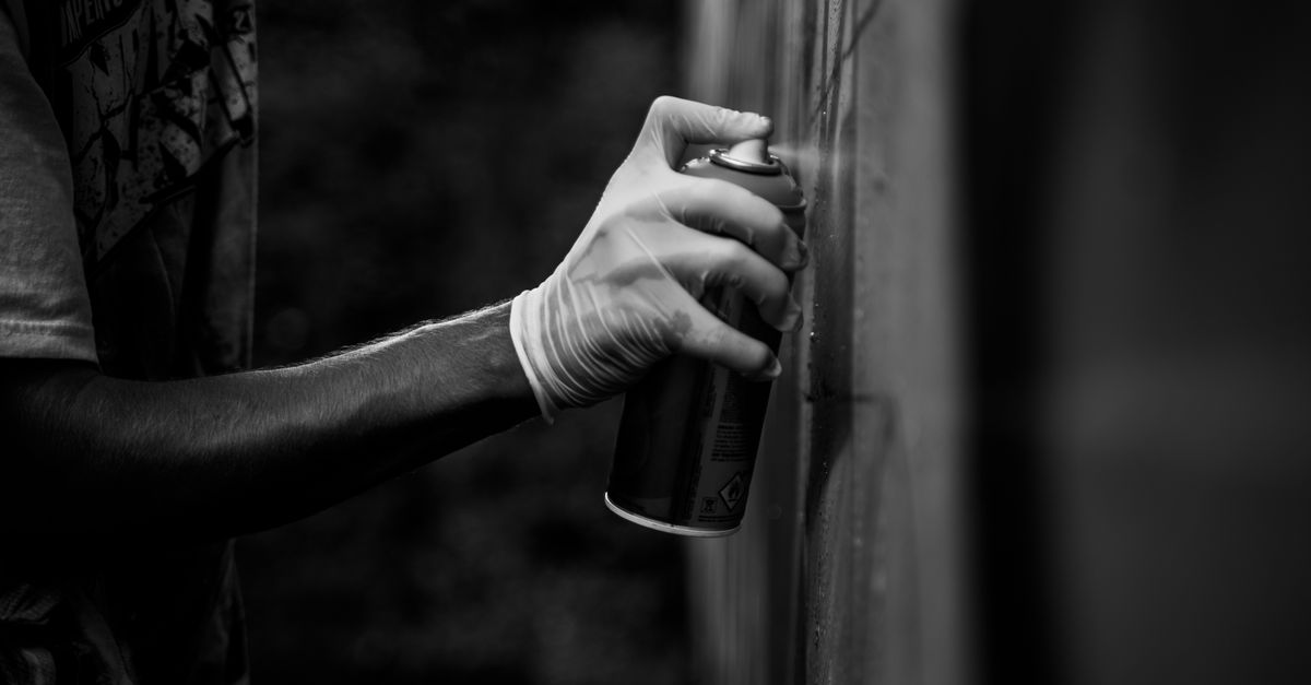 Mano sosteniendo un aerosol frente a una pieza pequeña sobre superficie de trabajo